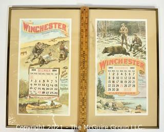 Two (2) Framed Under Glass Vintage Winchester Repeating Arms And Ammunition Calendars.  They each measure 19" long x 12".