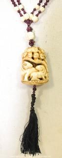 Carved Bone with Garnet Pendant on 32" Tassel Cord Necklace. 