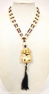 Carved Bone with Garnet Pendant on 32" Tassel Cord Necklace. 