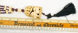 Carved Bone with Garnet Pendant on 32" Tassel Cord Necklace. 