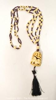 Carved Bone with Garnet Pendant on 32" Tassel Cord Necklace. 