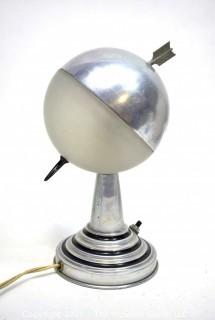 Art Deco Aluminum Globe Hemisphere “Saturn” Swiveling Table Lamp With Brass Arrow Details. Measures: 6"Wide X 6.5" Deep X 9.5" Tall. 