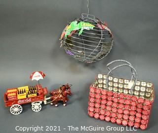 Three Decorative Items Including Coca - Cola Cast Iron Delivery Wagon With Driver, Horses and Crates, Tote Made of Bottle Caps & Wire Folk Art World Globe.