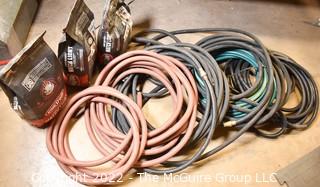 Assortment of Garden Hoses and 3 Bags of Charcoal