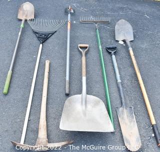 Collection of rakes, shovels, hoe and pick axe. 