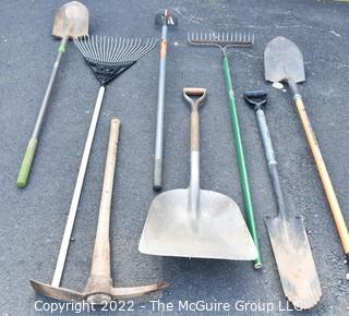 Collection of rakes, shovels, hoe and pick axe. 