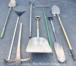 Collection of rakes, shovels, hoe and pick axe. 