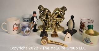 Group of Brass Thinker Bookends, Penquin Coin Bank, Souvenir items and Promotional Mugs.