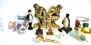 Group of Brass Thinker Bookends, Penquin Coin Bank, Souvenir items and Promotional Mugs.