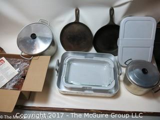 Collection of kitchenware including cast iron fry pans, roasting pan, and covered pyrex basking dish with carrying case 