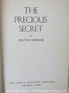 Collection of books including "The Precious Secret" by Fulton Oursler